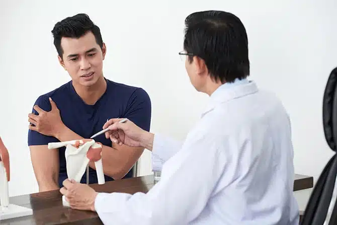 Chiropractor having a consultation with a patient suffers from shoulder injury