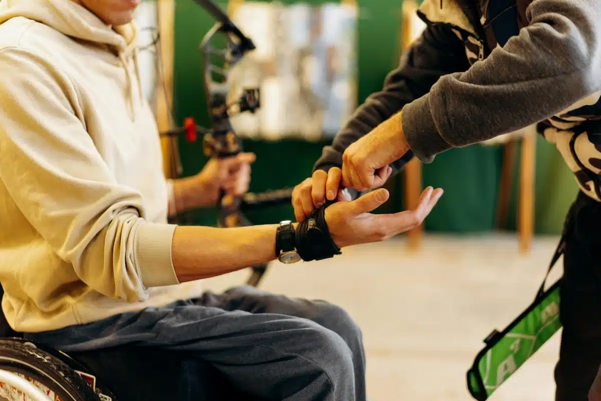 A man helping an athlete to wear his hand glove